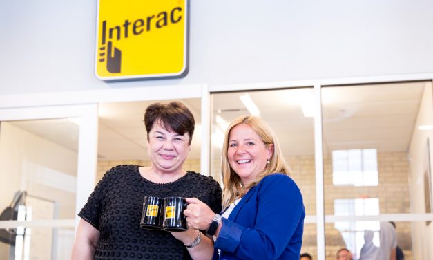 Debbie Gamble and Tricia Gruetzmacher clinking Interac mugs together in front of the new innovation lab