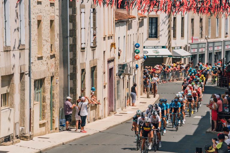 Athletes biking along city street during Tour de France