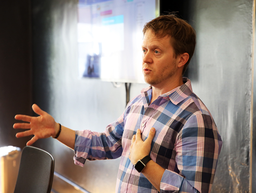 A person giving a speech in front of a chalk board.