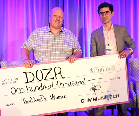 Kevin Forestell, co-founder of Dozr on stage with oversized cheque, and Rev Demo Day host.