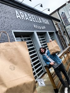 People picking up brown paper bags at Arabella Park