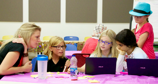 Instructor helping 4 participants on a 2 laptops